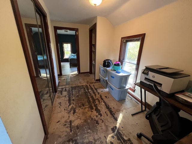 hallway with vaulted ceiling and baseboards