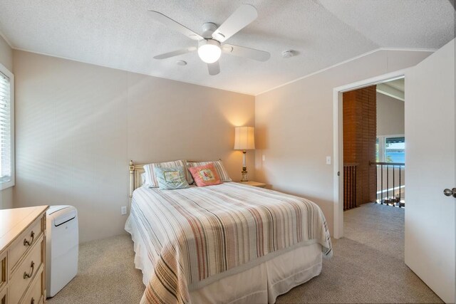 bedroom with a ceiling fan, lofted ceiling, light colored carpet, and a textured ceiling