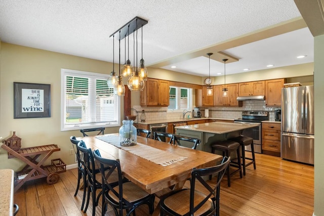 dining space with recessed lighting, baseboards, a textured ceiling, and light wood-style flooring