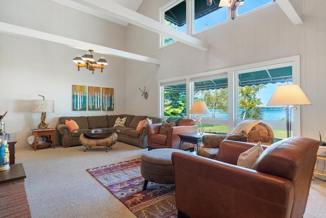 carpeted living area featuring an inviting chandelier, a towering ceiling, and beam ceiling