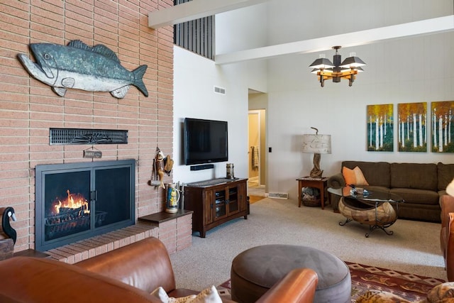 living area featuring visible vents, a brick fireplace, a chandelier, carpet floors, and a towering ceiling