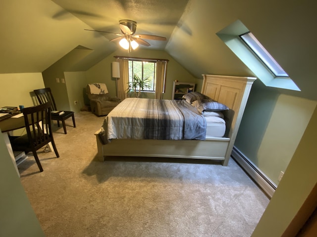 bedroom featuring ceiling fan, vaulted ceiling with skylight, baseboard heating, and carpet floors