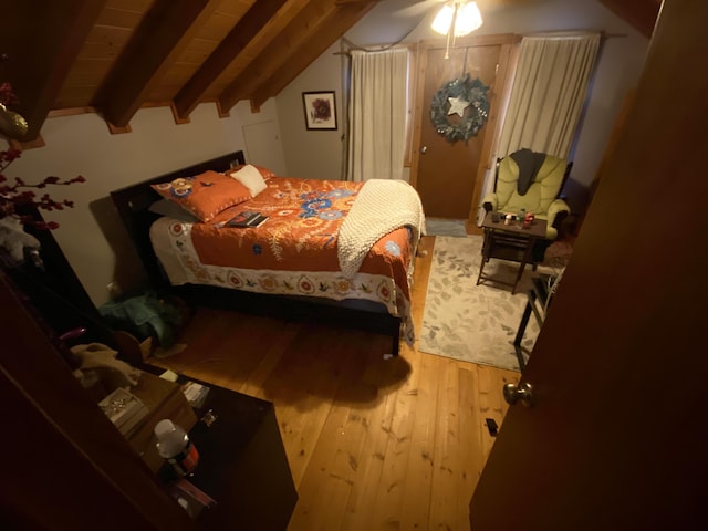 bedroom featuring hardwood / wood-style flooring, vaulted ceiling with beams, and a ceiling fan