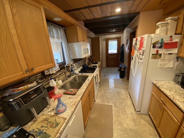 kitchen with a sink, white appliances, light stone counters, and brown cabinets