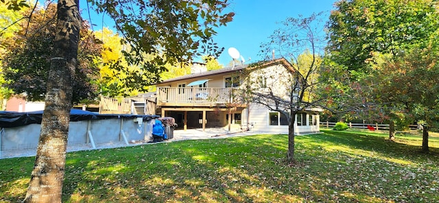 rear view of house featuring a covered pool, a lawn, a chimney, and a deck