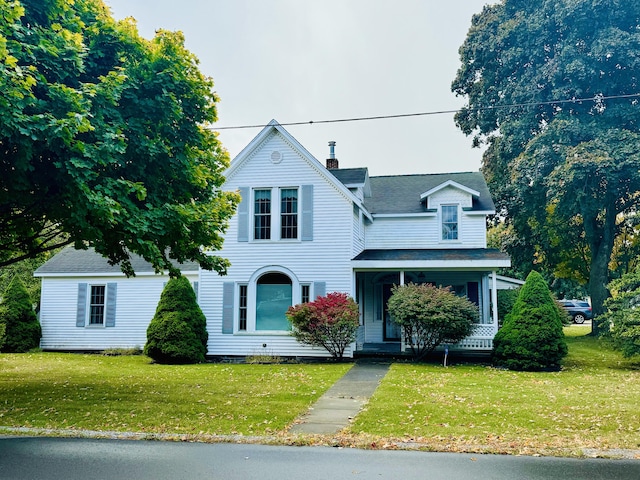 view of front of property with covered porch, a chimney, and a front lawn