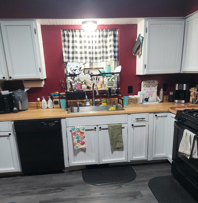 kitchen with a sink, dark wood-style floors, black appliances, and white cabinets