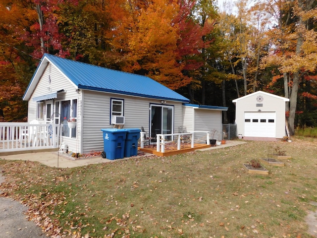 view of front facade with a wooden deck, an outdoor structure, a front lawn, a garage, and metal roof