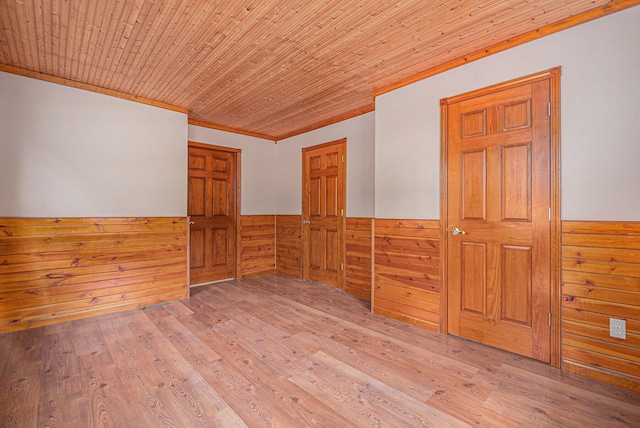 unfurnished room with wood finished floors, wood ceiling, wood walls, and wainscoting