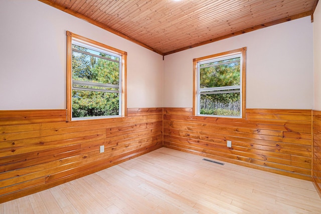 spare room featuring visible vents, wooden walls, a wainscoted wall, wooden ceiling, and wood finished floors