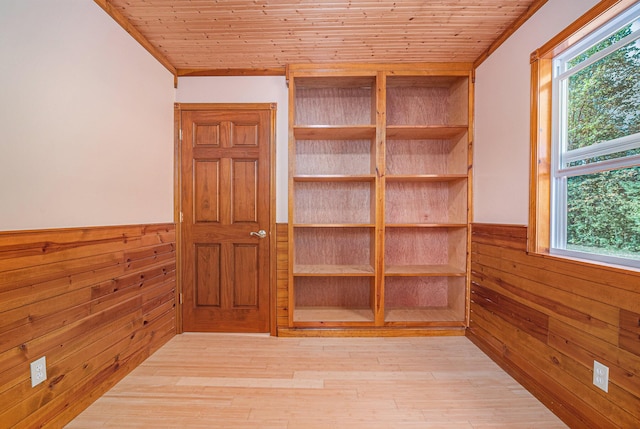 empty room featuring wainscoting, wood walls, wooden ceiling, and wood finished floors