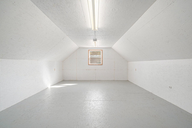 additional living space with vaulted ceiling and a textured ceiling