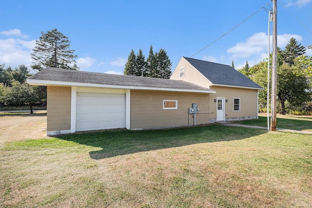 back of house with a garage, driveway, and a yard