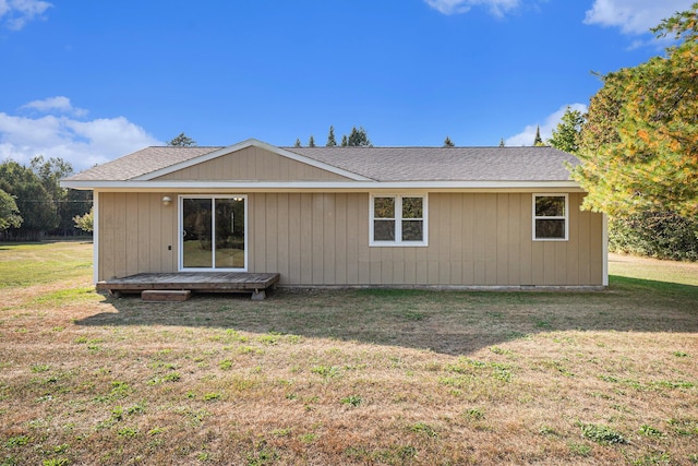 back of property with a lawn and a shingled roof