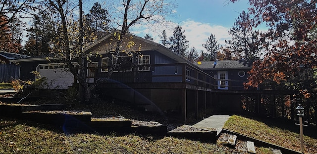 rear view of property with an attached garage and fence