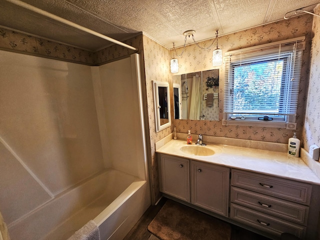 full bath featuring tub / shower combination, wallpapered walls, vanity, and a textured ceiling