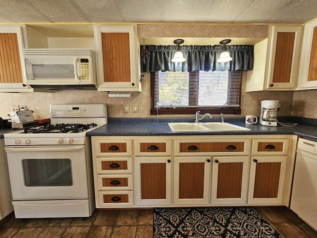 kitchen featuring dark countertops, white appliances, and a sink