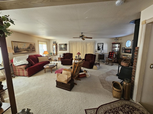 carpeted living area with ceiling fan, a wood stove, and a textured ceiling