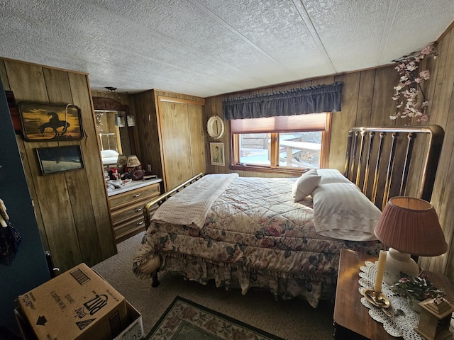 carpeted bedroom featuring wooden walls and a textured ceiling