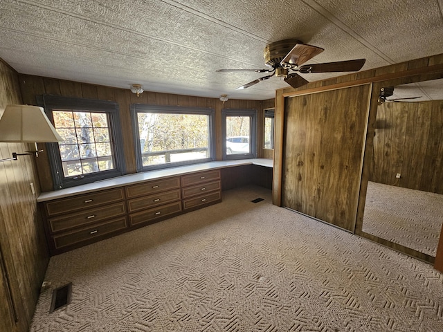 unfurnished bedroom featuring visible vents, wood walls, carpet, and a textured ceiling