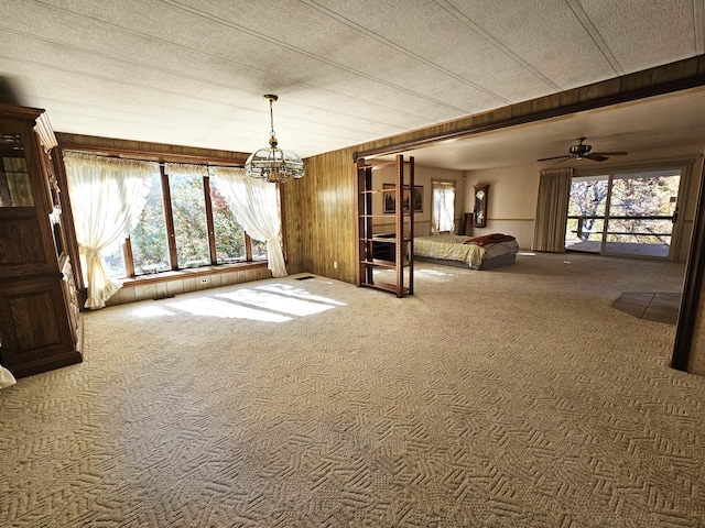 interior space featuring wooden walls, carpet, and ceiling fan with notable chandelier