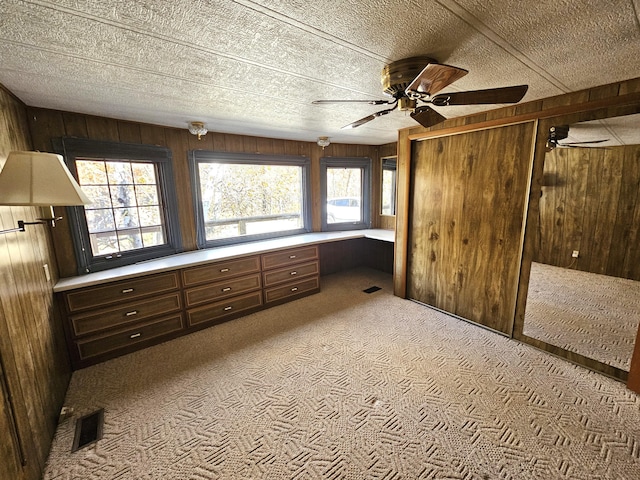 unfurnished bedroom with visible vents, wood walls, carpet flooring, and a textured ceiling