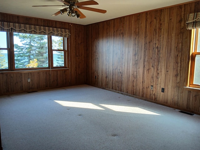 spare room with visible vents, baseboards, wood walls, and carpet flooring