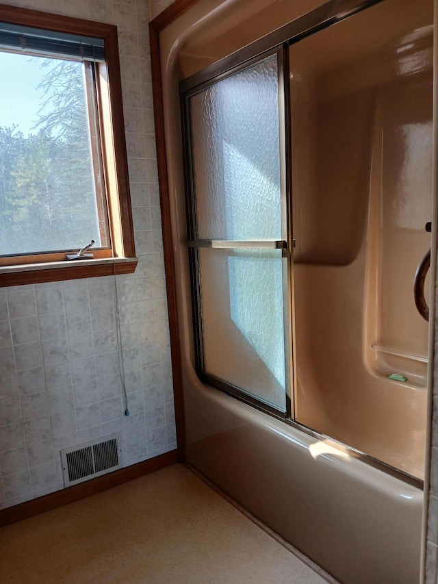 bathroom with enclosed tub / shower combo and visible vents