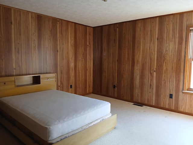 carpeted bedroom featuring visible vents, wood walls, and a sauna