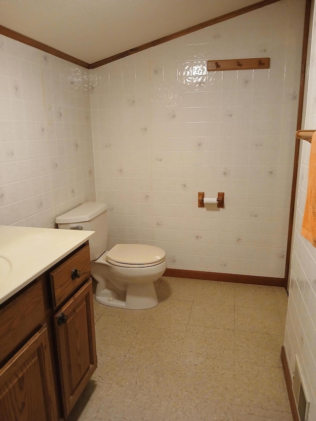 bathroom with tile patterned floors, toilet, vanity, and tile walls