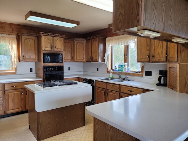 kitchen with black appliances, a sink, brown cabinetry, light countertops, and light floors