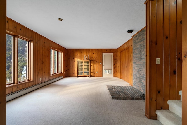 living area featuring a baseboard heating unit, stairway, wooden walls, and carpet