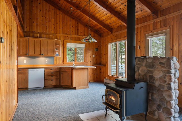 kitchen featuring a wood stove, wooden walls, and white dishwasher
