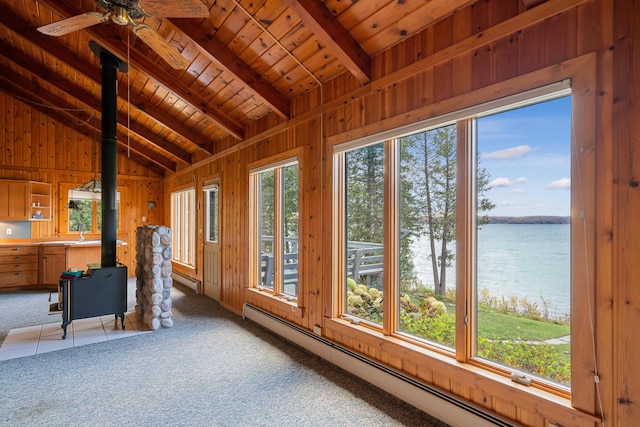 unfurnished sunroom with a water view, a baseboard radiator, wood ceiling, a wood stove, and a sink
