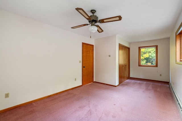 empty room featuring baseboard heating, light colored carpet, a ceiling fan, and baseboards