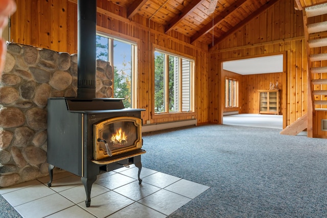 interior space with wooden walls, wood ceiling, carpet flooring, a wood stove, and a baseboard radiator