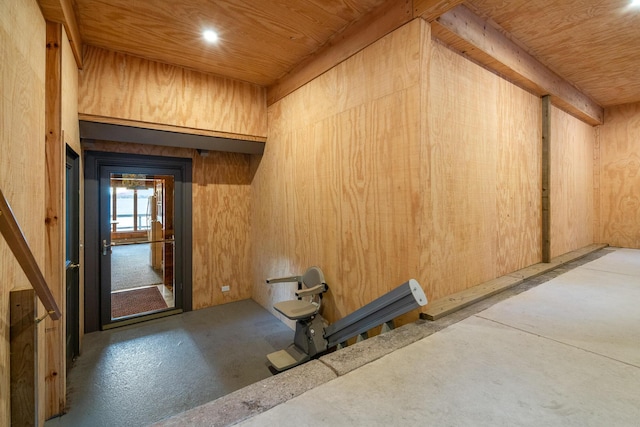 interior space featuring wooden walls, concrete flooring, and wooden ceiling