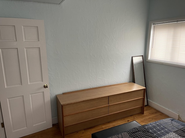 unfurnished bedroom featuring wood finished floors, baseboards, and a textured wall