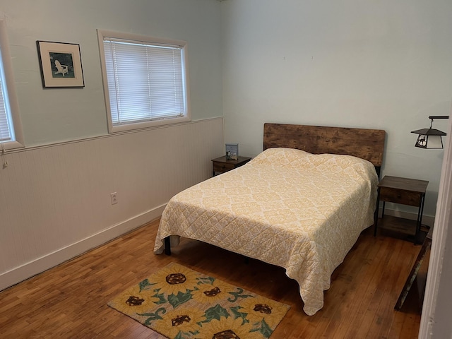 bedroom with a wainscoted wall and hardwood / wood-style floors