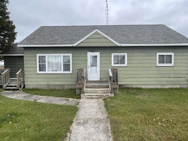 bungalow featuring a front lawn and roof with shingles