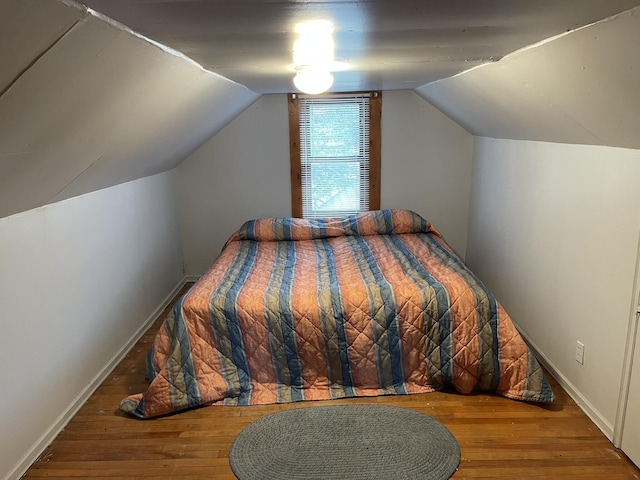 bedroom featuring baseboards, wood finished floors, and vaulted ceiling