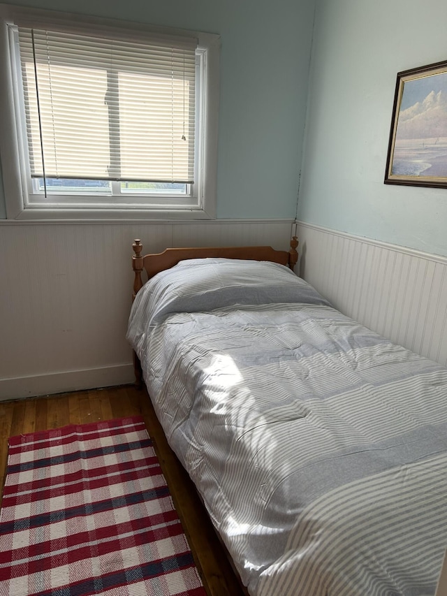 bedroom with a wainscoted wall and wood finished floors