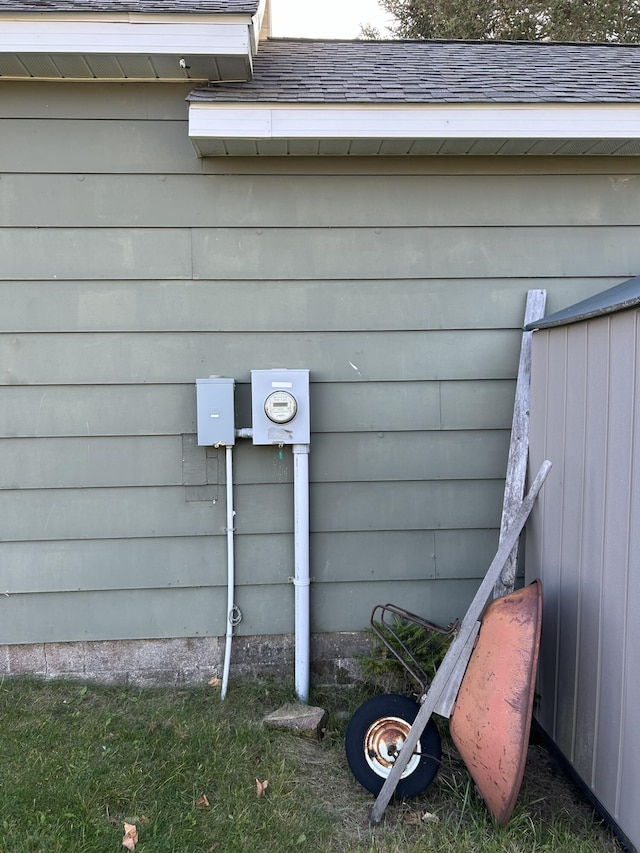 exterior details with electric meter and a shingled roof