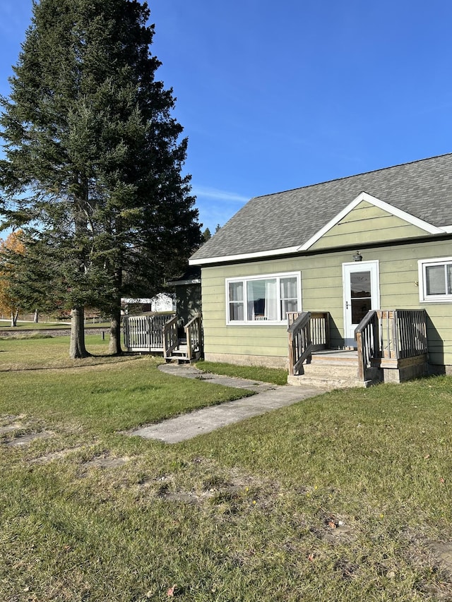 view of front of property with a shingled roof and a front lawn