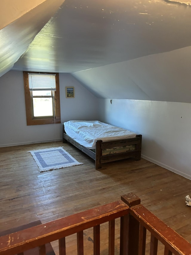 unfurnished bedroom with baseboards, lofted ceiling, and hardwood / wood-style flooring