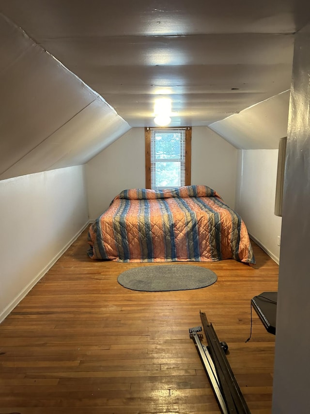 bedroom featuring baseboards, lofted ceiling, and wood finished floors