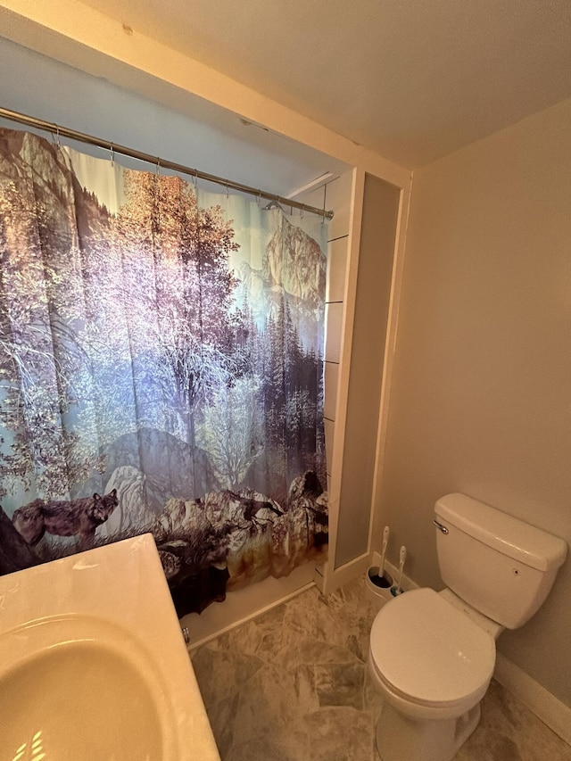 bathroom with a sink, curtained shower, baseboards, and toilet