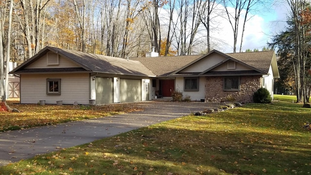 view of front facade with a garage, a chimney, a front yard, and aphalt driveway