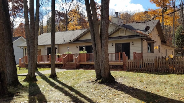 rear view of house with a wooden deck, a lawn, and a chimney