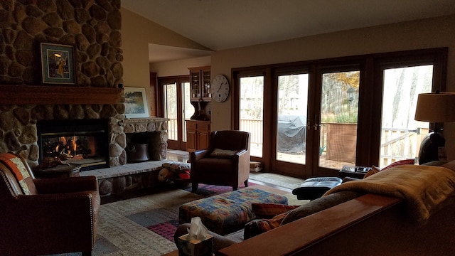 living area with a stone fireplace and vaulted ceiling